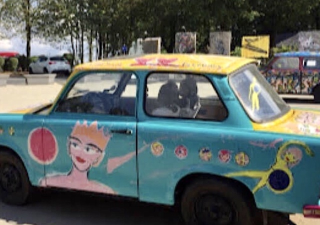 « Une voiture peintes de couleurs vives devant le Bastogne War Museum »